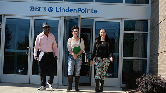 An exterior shot of the LindenPointe building with three students exiting the doors.
