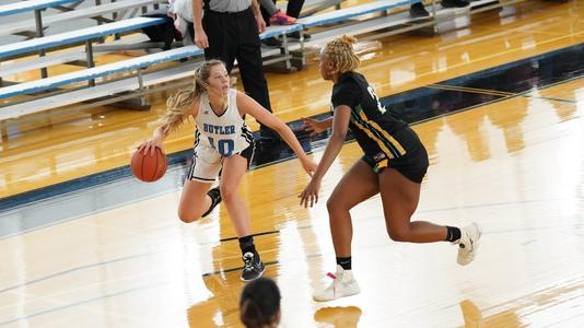 A women's basketball player dribbling the ball away from an opponent