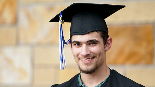 Image: a male graduate wearing a black cap and gown