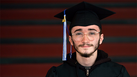 Image: a male graduate wearing a black cap and gown