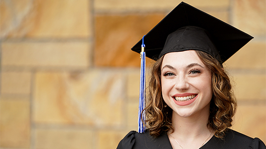 Image: photo of a female graduate wearing a black cap and gown