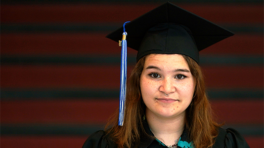 Image: photo of a female graduate wearing a black cap and gown